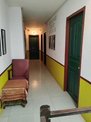 a hallway with a chair and a green door at Soben Cafe Guesthouse & Restaurant in Siem Reap