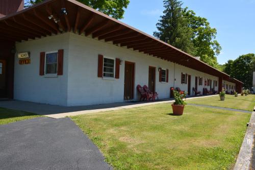 a small white building with a grass yard in front of it at The Village Motel in Richfield Springs