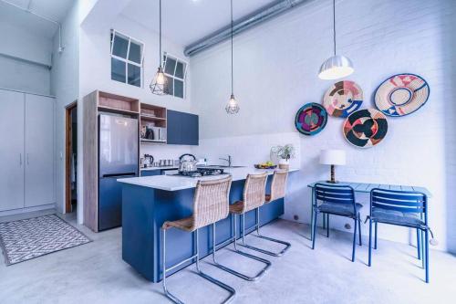 a kitchen with a blue island and chairs in it at Modern 1 bedroom apartment in Braamfontein Werf in Johannesburg