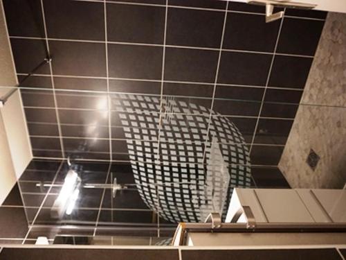 La salle de bains est pourvue de murs carrelés noirs et d'un miroir. dans l'établissement Studio 4 pers, proche pistes et commerces, animaux acceptés - FR-1-636-167, à Orcières