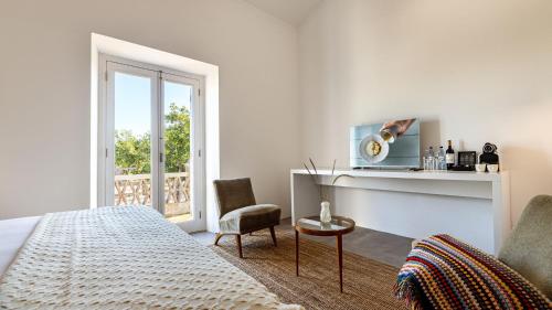 - une chambre blanche avec un lit et une chaise dans l'établissement Quinta do Santo - Évora, à Évora