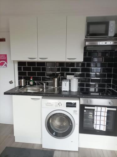 a kitchen with a washing machine and a sink at Private Studio on Finchley Road in London