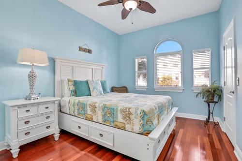 Schlafzimmer mit blauen Wänden, einem Bett und einem Deckenventilator in der Unterkunft Bayfront Bounty in Clearwater Beach