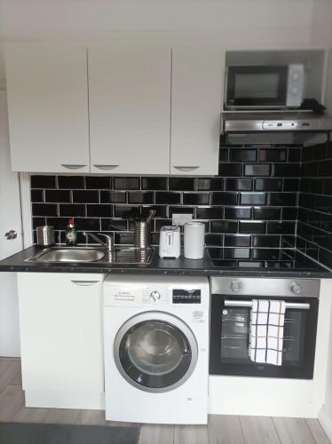 a kitchen with a washing machine and a microwave at Private Studio on Finchley Road in London