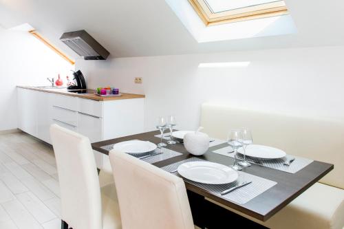 a dining room table with white chairs and a kitchen at Le Boca in Les Waleffes
