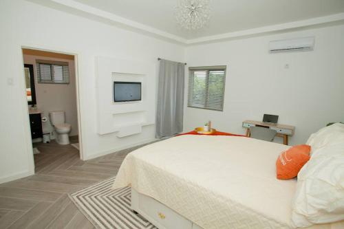 a white bedroom with a bed and a television at FunTime Vacation Home in Kingston