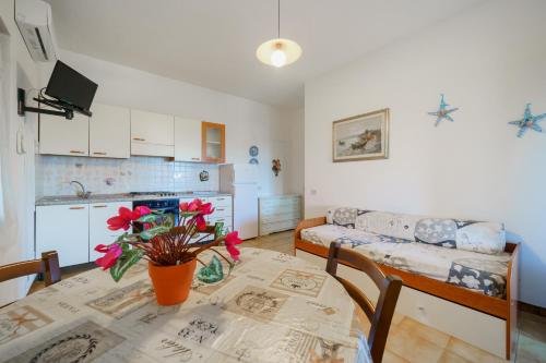 a kitchen and living room with a table with red flowers on it at Dimora Capoliveri in Capoliveri