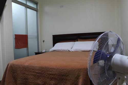 a bedroom with a bed with a fan at Casa Leon 5 min away from the Airport in Lima