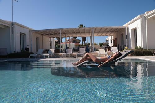 a woman laying on a raft in a swimming pool at CORALLI DEL PLEMMIRIO in Siracusa