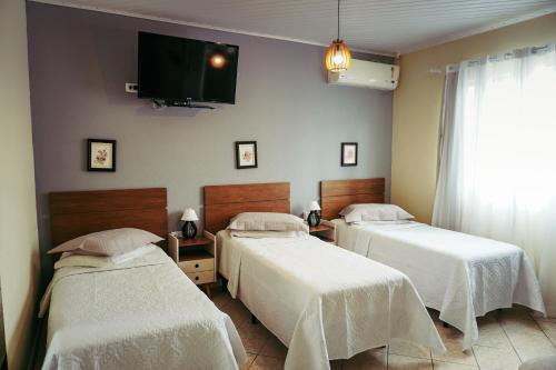 two beds in a room with a tv on the wall at Pousada UpSerra in Urubici