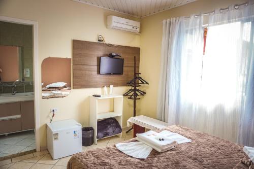 a bedroom with a bed and a tv on the wall at Pousada UpSerra in Urubici