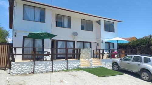 a white house with a car parked in front of it at Departamentos villamar guanaquero in Coquimbo