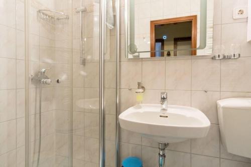 ein weißes Bad mit einem Waschbecken und einer Dusche in der Unterkunft "Vier Jahreszeiten", Haus I, Wohnung 87 in Großenbrode