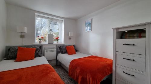 1 Schlafzimmer mit 2 Betten und orangefarbenen Kissen in der Unterkunft May View - Luxury Sea View Apartment - Millendreath, Looe in Looe