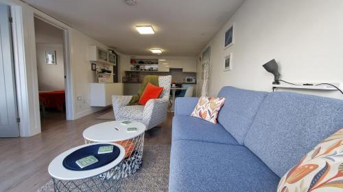ein Wohnzimmer mit einem blauen Sofa und 2 Tischen in der Unterkunft May View - Luxury Sea View Apartment - Millendreath, Looe in Looe