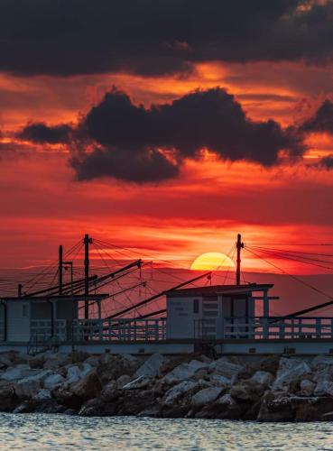 a building on the beach with a sunset in the background at Villa Lida Apartment, in collina con ampio terrazzo e vista mare in Giulianova