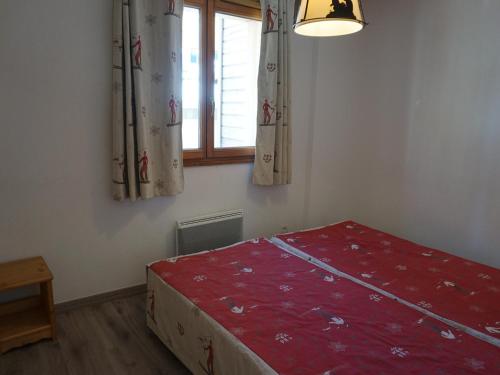 - une chambre avec un lit rouge et une fenêtre dans l'établissement 3 pièces à Orcières, 6 pers, piscine, parking, wifi gratuit - FR-1-636-1, à Orcières