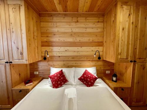 a bed in a wooden room with two red pillows at Hotel ŠURC in Kranjska Gora
