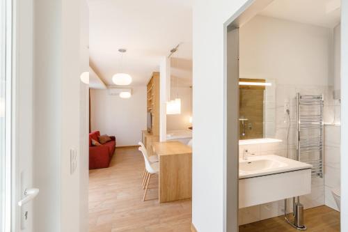 a bathroom with a sink and a living room at La Bella Centrum apartmanok Piros/Sárga in Hévíz
