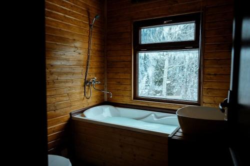 baño de madera con bañera y ventana en Hill SilENCE MESTIA, en Mestia