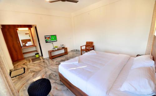a bedroom with a large white bed and a mirror at 10 Degrees North By Avni Holidays in Idukki