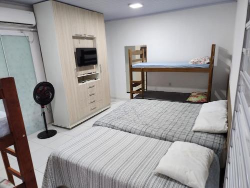 een kamer met 2 bedden, een bureau en een televisie bij BARREIRINHAS CHALÉ 12 PORTO DOS LENÇÓIS in Barreirinhas