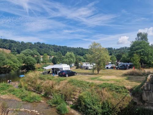 a campsite with a car parked next to a river at Chalet Hohllay in Reisdorf