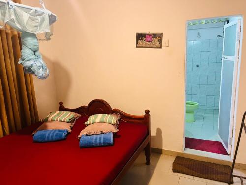 - une chambre avec un lit rouge et 2 oreillers dans l'établissement Sinharaja Tour Hostel, à Deniyaya