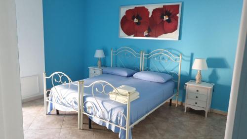 een blauwe slaapkamer met een bed met rode bloemen aan de muur bij B&B Pittoresco in Specchia