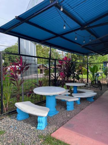 a group of tables and benches under a blue canopy at The Sweet Escape Cabinas in Sierpe