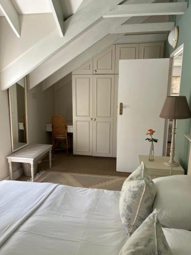 a bedroom with a bed and a desk and a door at Constantia cottage- Warblers Nest in Cape Town