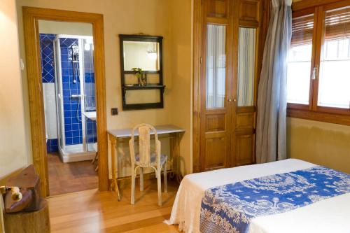a bedroom with a bed and a desk with a mirror at La Chatarrería de Ferreros in Otero de Herreros