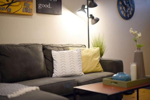 a living room with a gray couch with a yellow pillow at HostWise Stays - The Ocala - Free Parking, Cool Space, Spiral Stairs in Pittsburgh