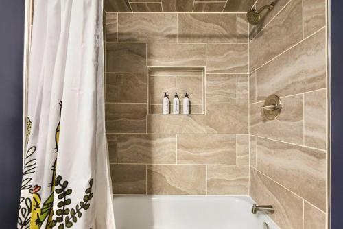 baño con bañera y ducha con 2 botellas en HostWise Stays - The Edmond - Bloomfield Apartment in a great location!, en Pittsburgh