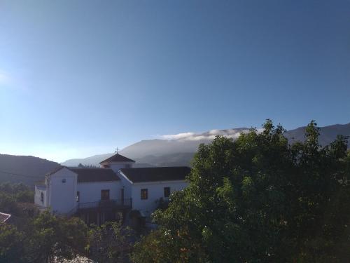 a white house with a mountain in the background at El Violin Experiencia Adults only in Melegis