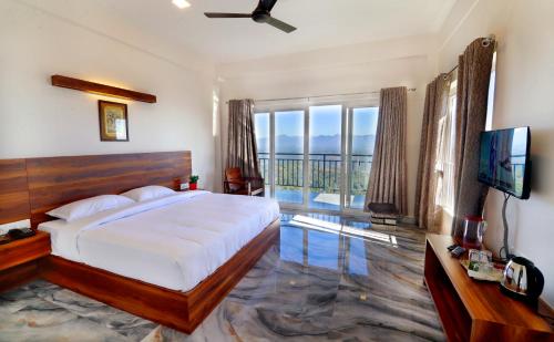 a bedroom with a bed and a television and a balcony at 10 Degrees North By Avni Holidays in Idukki