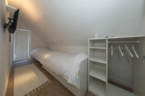 a small white bedroom with a bed and a desk at Kuća za odmor Secret place in Lovinac