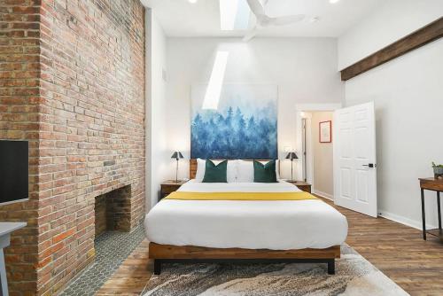 - une chambre avec un grand lit et un mur en briques dans l'établissement HostWise Stays - The Larryville - Amazing Bathroom, Perfect Location, Custom Build, à Pittsburgh