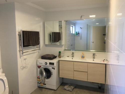 a bathroom with a washing machine and a sink at Parkline Apartments Perth in Perth