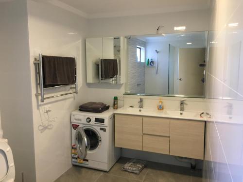 a bathroom with a washing machine and a sink at Parkline Apartments Perth in Perth