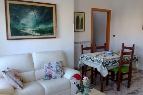 sala de estar con mesa y sofá blanco en GIRASOLE a due passi dal mare, en Minturno