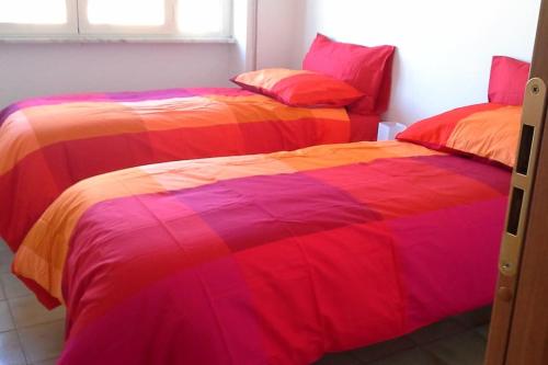 Habitación con 2 camas con sábanas coloridas. en GIRASOLE a due passi dal mare, en Minturno