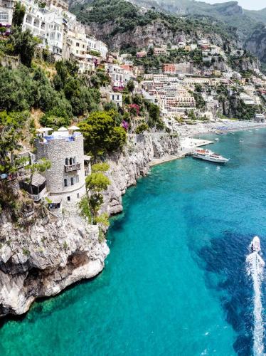 a boat in a body of water next to a mountain at Villa Torre Trasita luxury suites in Positano