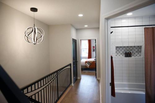 a hallway with a bathroom with a bath tub and a chandelier at HostWise Stays - The Peralta - Brand New, Great Kitchen, Theater Room in Pittsburgh