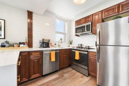 a kitchen with wooden cabinets and a stainless steel refrigerator at HostWise Stays - Grandview Balcony with Stunning Skyline Views in Pittsburgh