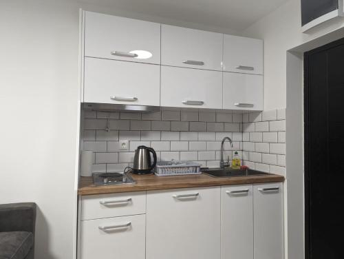 a kitchen with white cabinets and a sink at Kod Strica in Kopaonik