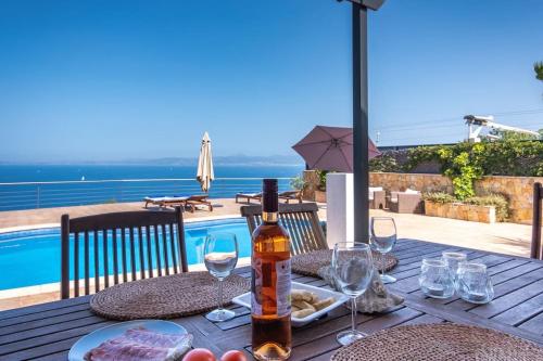 uma mesa de madeira com uma garrafa de vinho e copos de vinho em Amazing sea views Villa Voramar with pool em Llucmajor