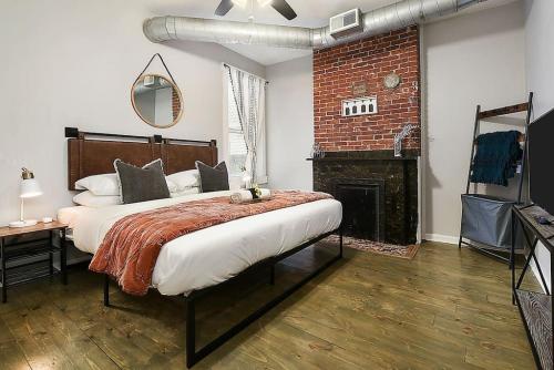 1 dormitorio con 1 cama grande y pared de ladrillo en HostWise Stays - The James Apt 1 - Patio, Free Street Parking, en Pittsburgh