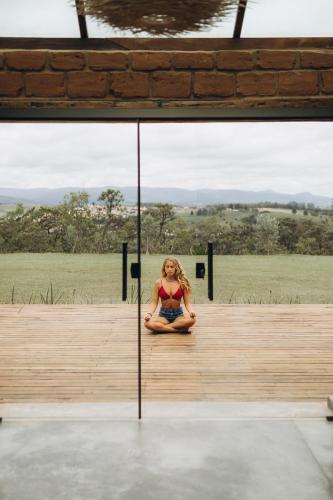 a woman is sitting on a wooden deck at Pousada Sete Quedas in Carrancas