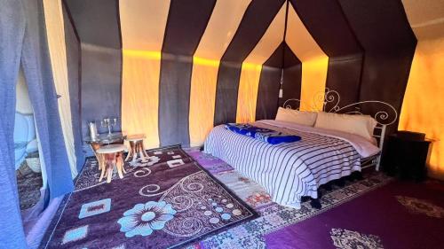 a bedroom with a bed with a striped wall at Sahara Luxury Camp in Zagora